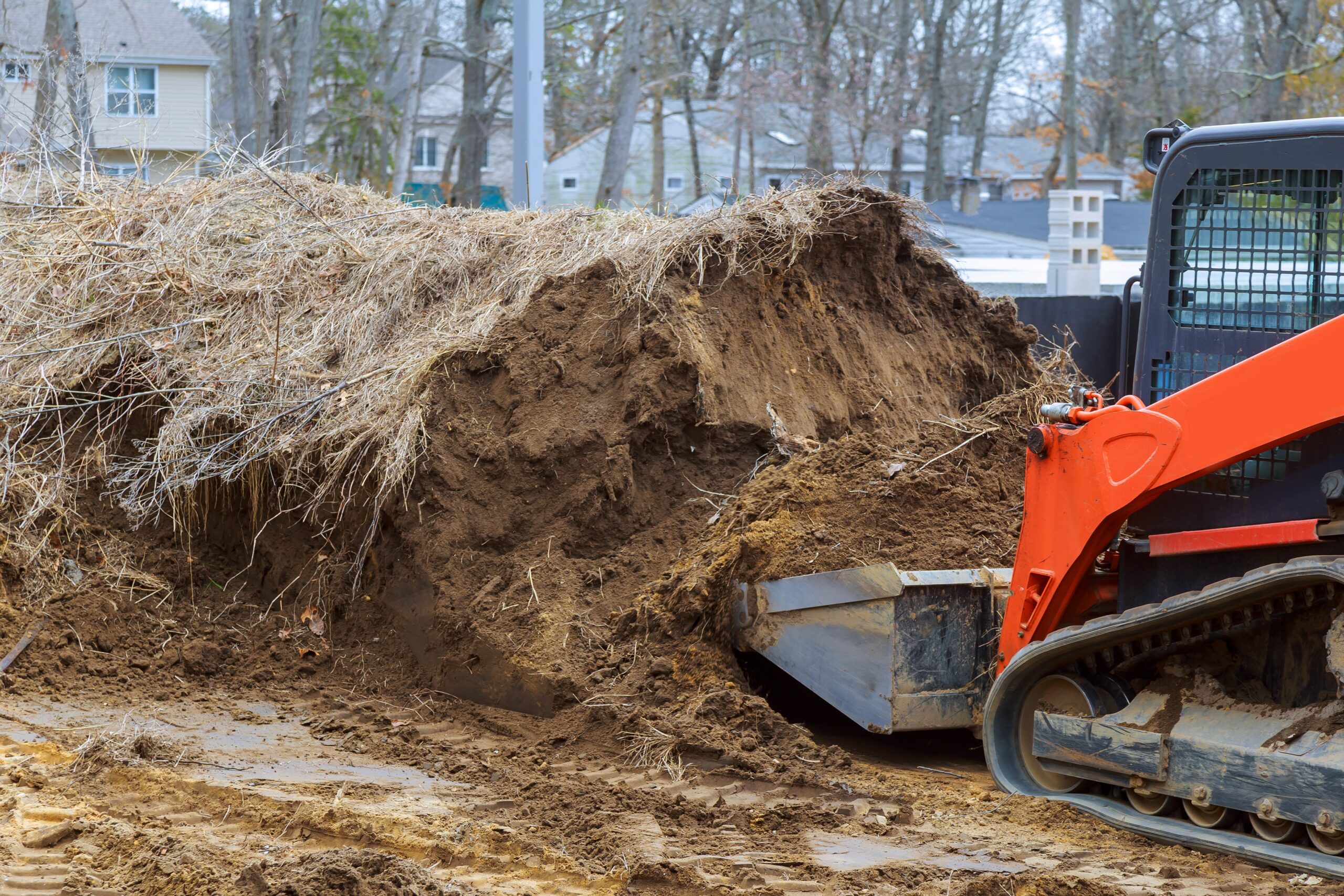 Backhoe excavator parked on a construction site with a dirt mound in the foreground